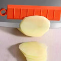 Potato being sliced with a red and orange slicer on a gray surface.